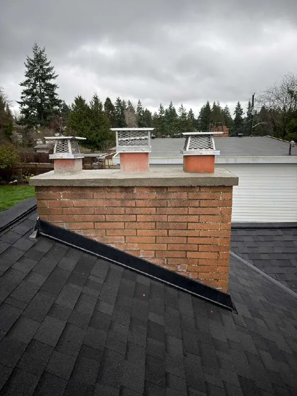 Three cast chimney caps on a wide brick chimney with a new crown