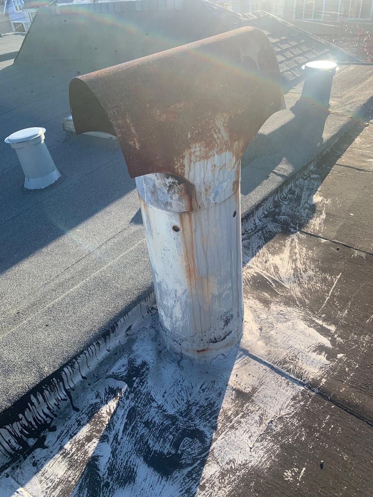 A rusted flue cap on an exposed roof after a winter
